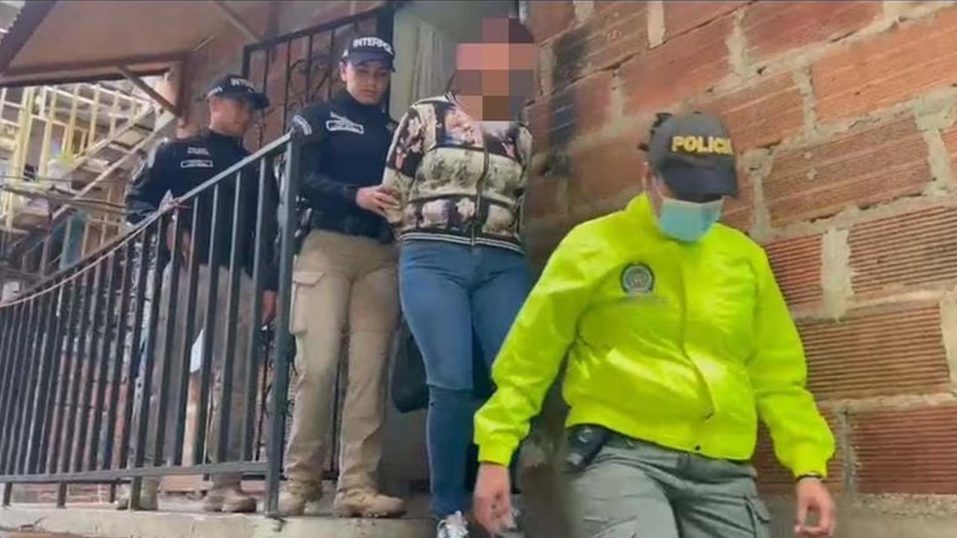 La mujer capturada siendo retirada de su vivienda bajo la compañía de oficiales de la Policía 