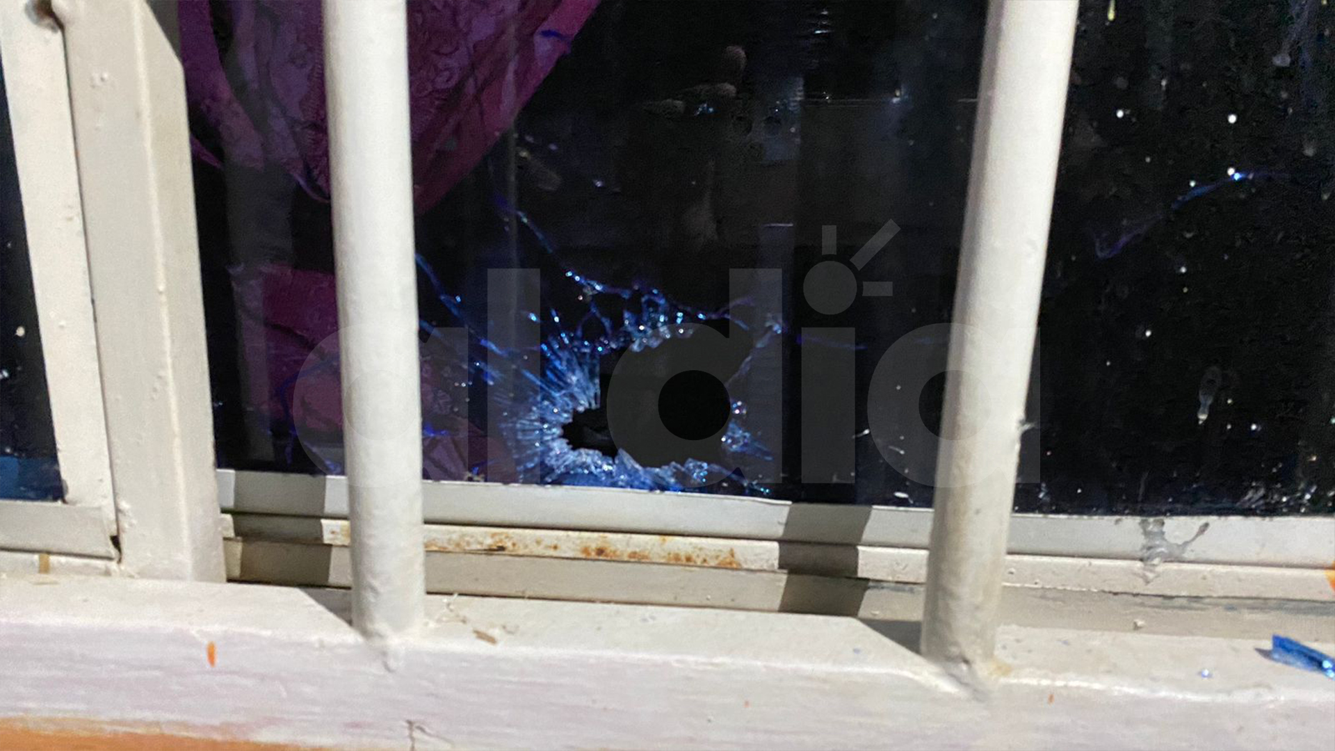 Uno de los impactos de bala y su perforación en una de las ventanas de la vivienda