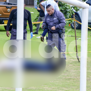 Peritos del CTI de la Fiscalía realizan el levantamiento del cadáver del hombre que quedó tendido junto a una cancha de fútbol.