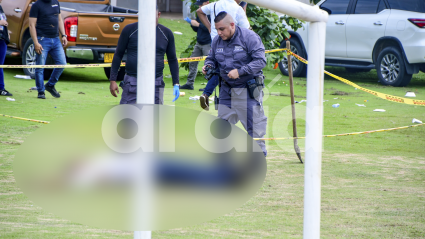 Peritos del CTI de la Fiscalía realizan el levantamiento del cadáver del hombre que quedó tendido junto a una cancha de fútbol.